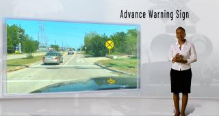 a woman next to a screen showing a road sign